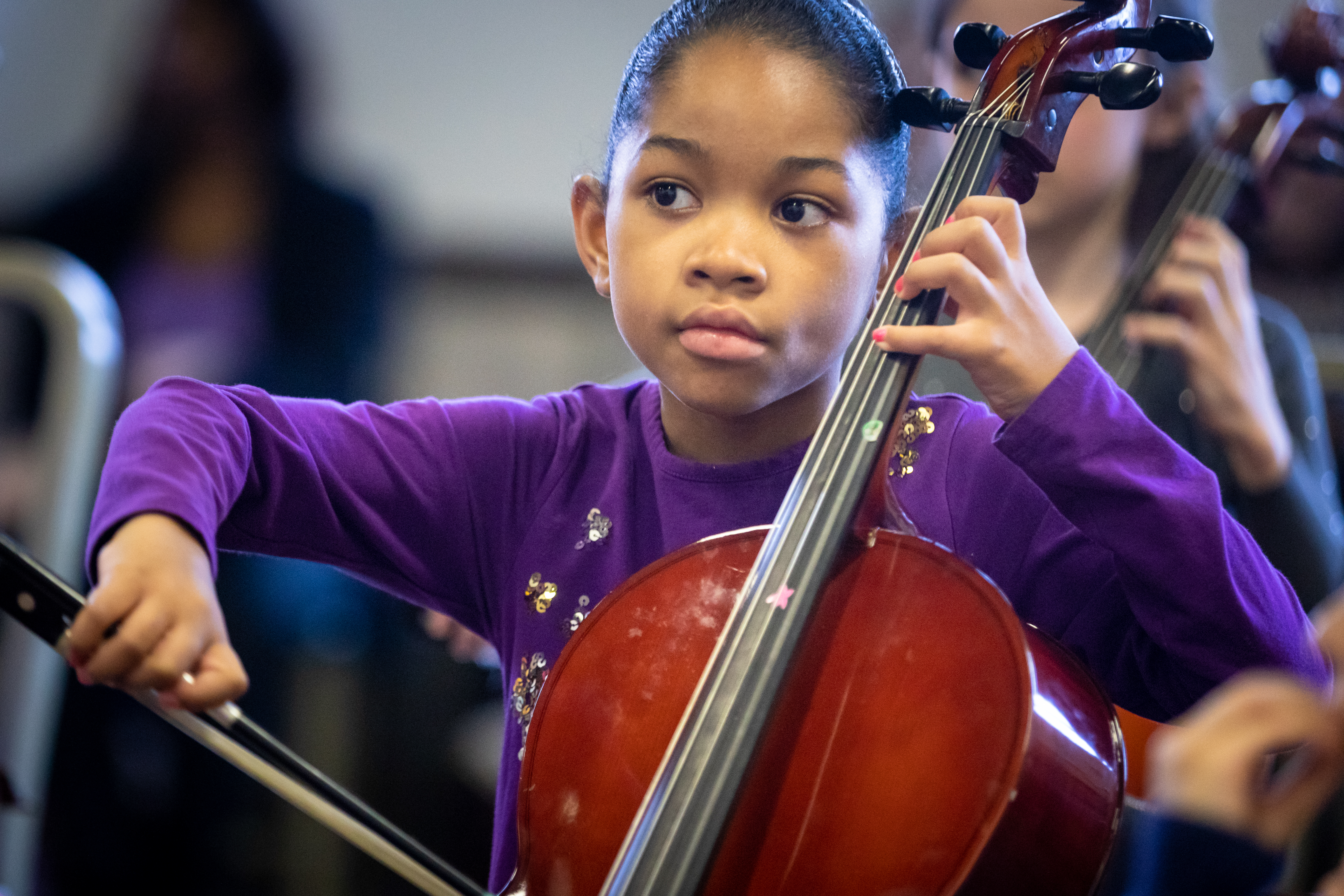 Girl wearing purple sweater playing a cello
